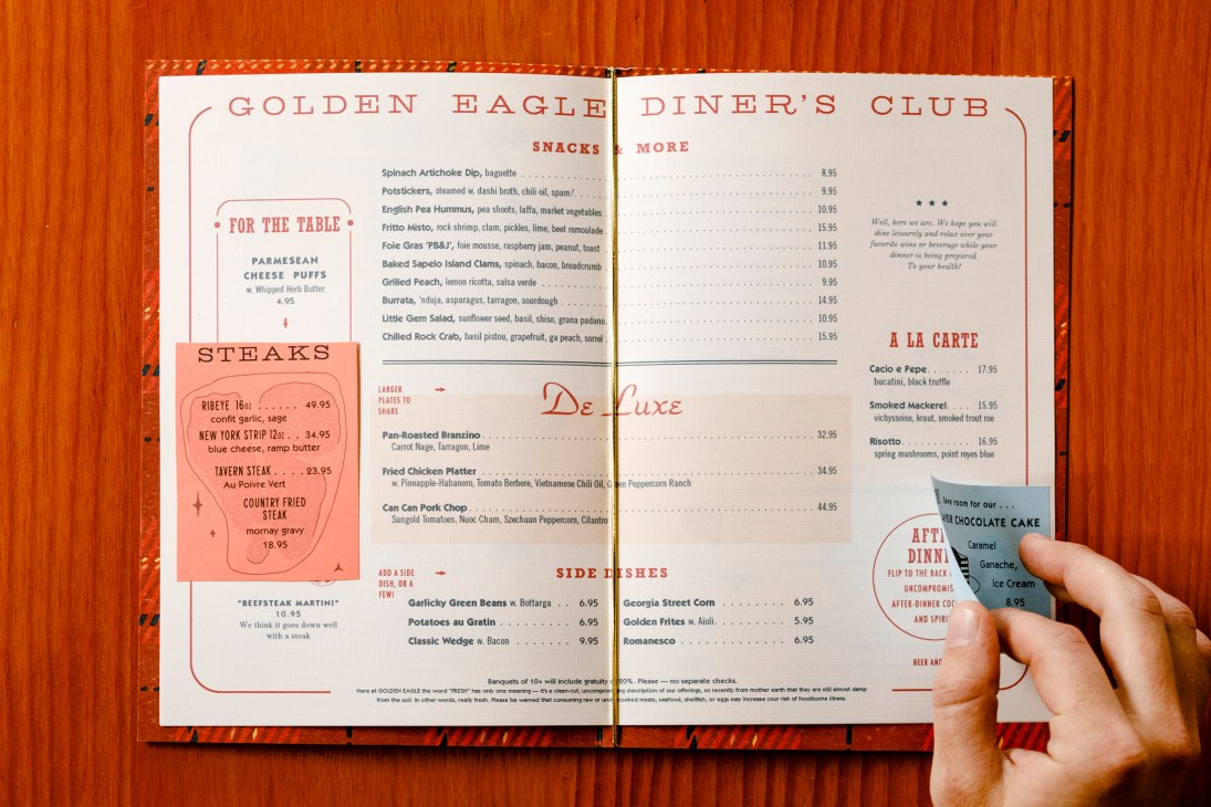 Hand holding open a Golden Eagle Diner's Club menu showing steaks, snacks, and de luxe dishes