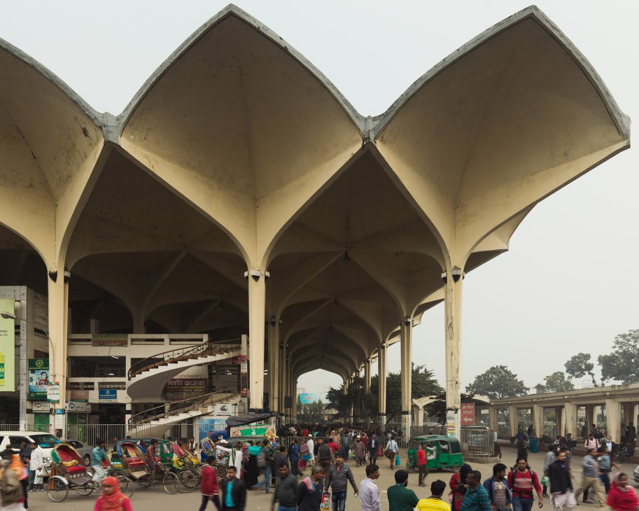 Kamalapur Railway Station's modernist concrete vaulted structure with crowds and rickshaws below.