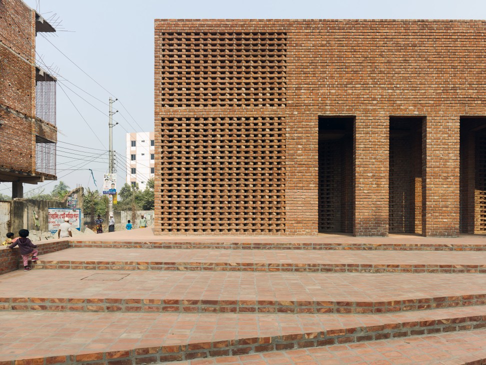 Brick exterior of Bait Ur Rouf Mosque with geometric perforated pattern and dark doorways.