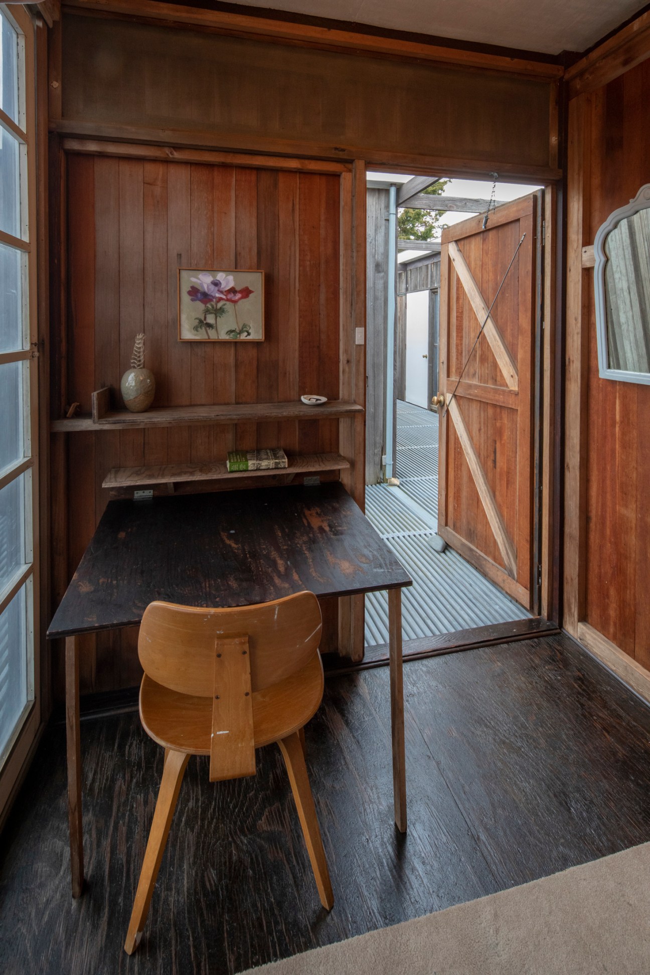 Writing desk in a guest bedroom at Hatch Cottage with wood paneling and built-in shelves.