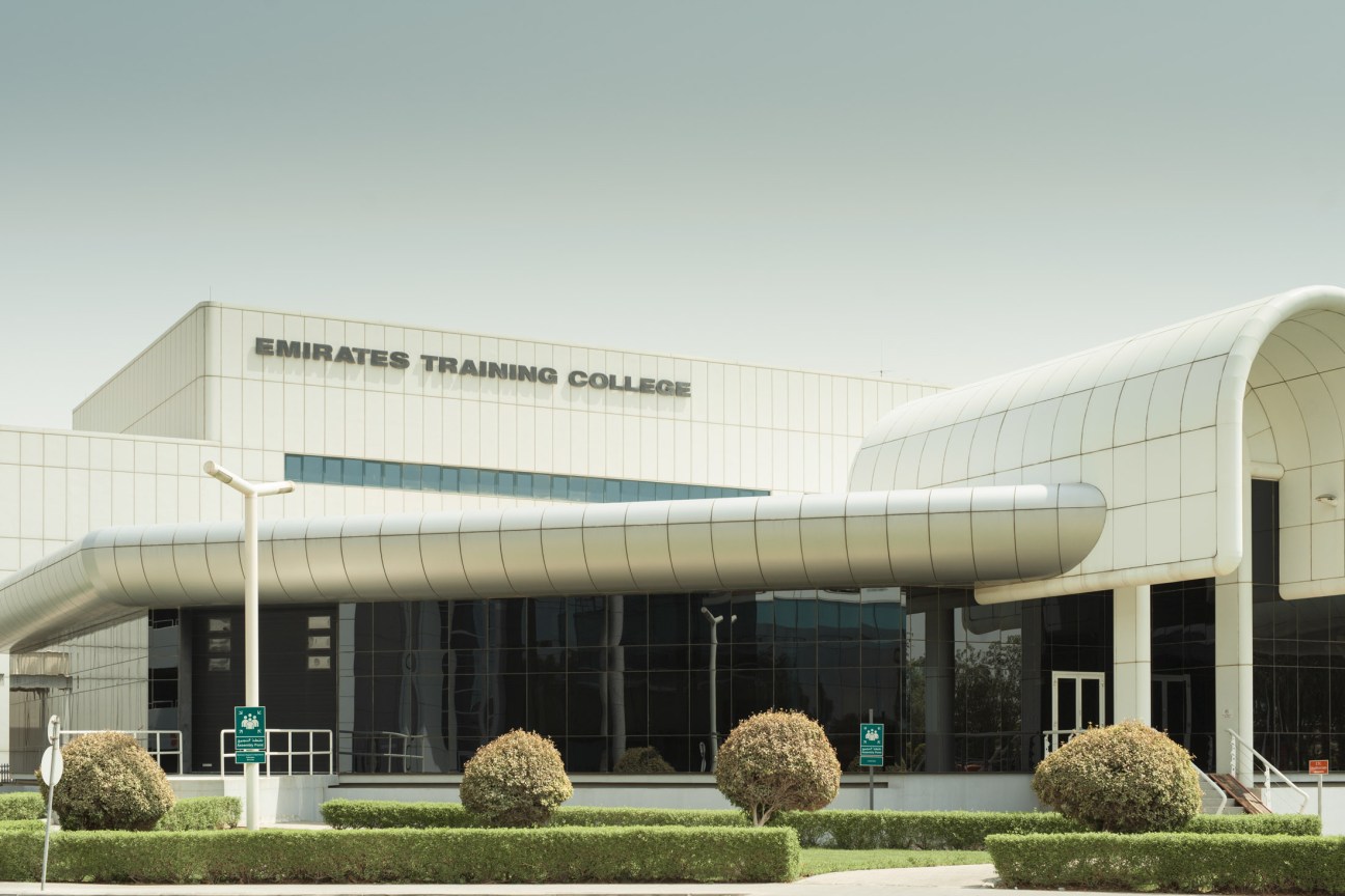 Emirates Training College exterior with distinctive curved metallic aircraft fuselage design and modern white building.
