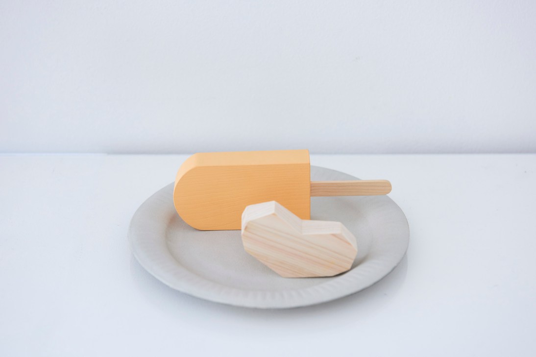 Wooden popsicle and biscuit-shaped toys on a white plate by Ryota Nishimoto from Hoek.