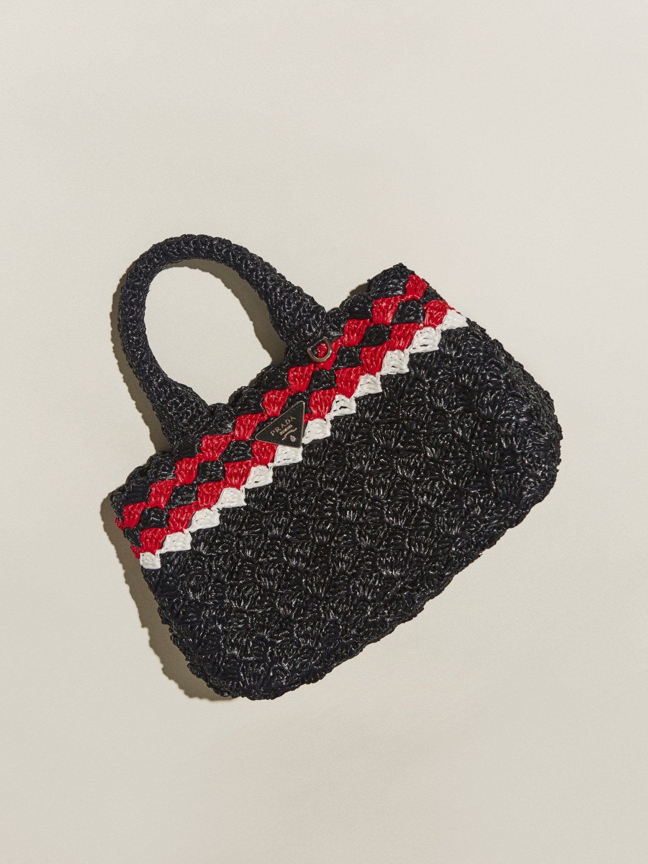 Black woven Prada bag with red and white chevron stripe detail.