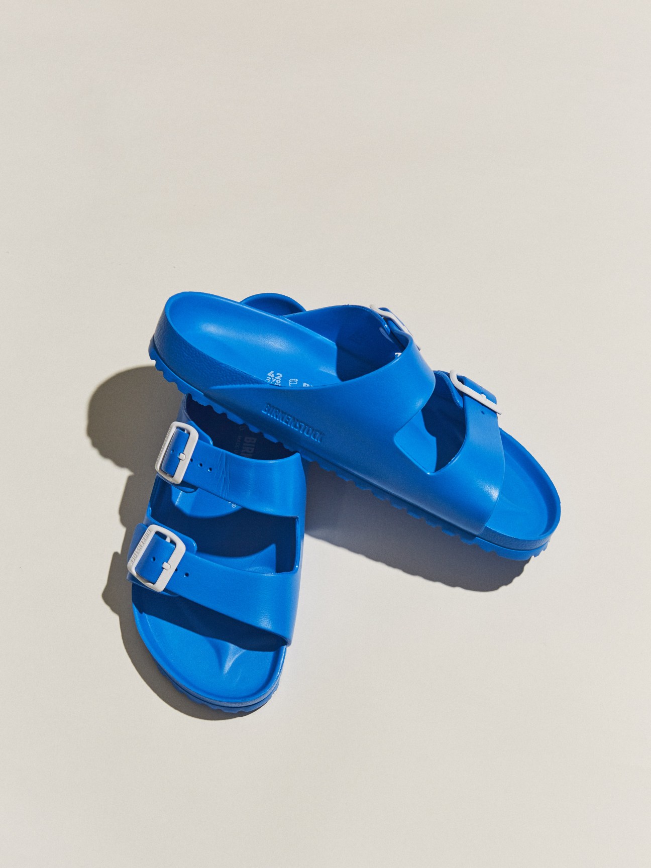 Bright blue Birkenstock sandals with buckle straps on a neutral background.