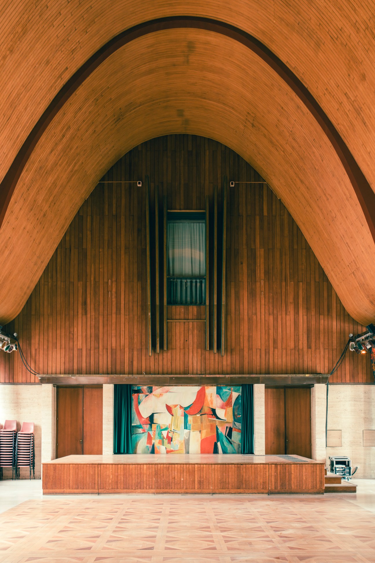 Interior of the Grande Salle in Rouen's Halle aux Toiles showing curved wooden ceiling and colorful stage backdrop