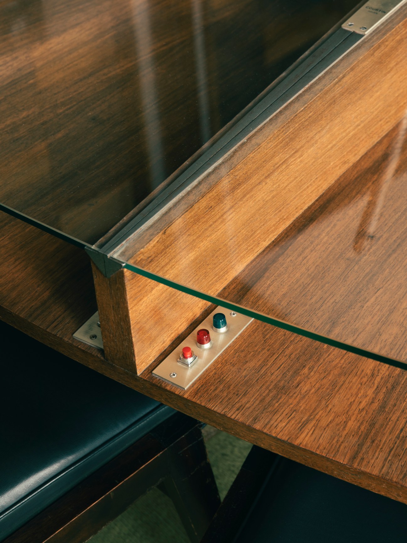 Control buttons mounted in wooden panel with glass top on council room table