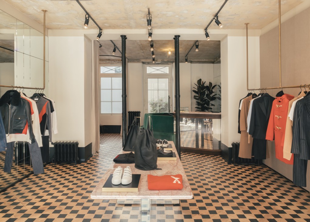 Ami women's shop interior in Saint-Germain-des-Prés with clothing racks, geometric floor tiles, and red heart logo details.