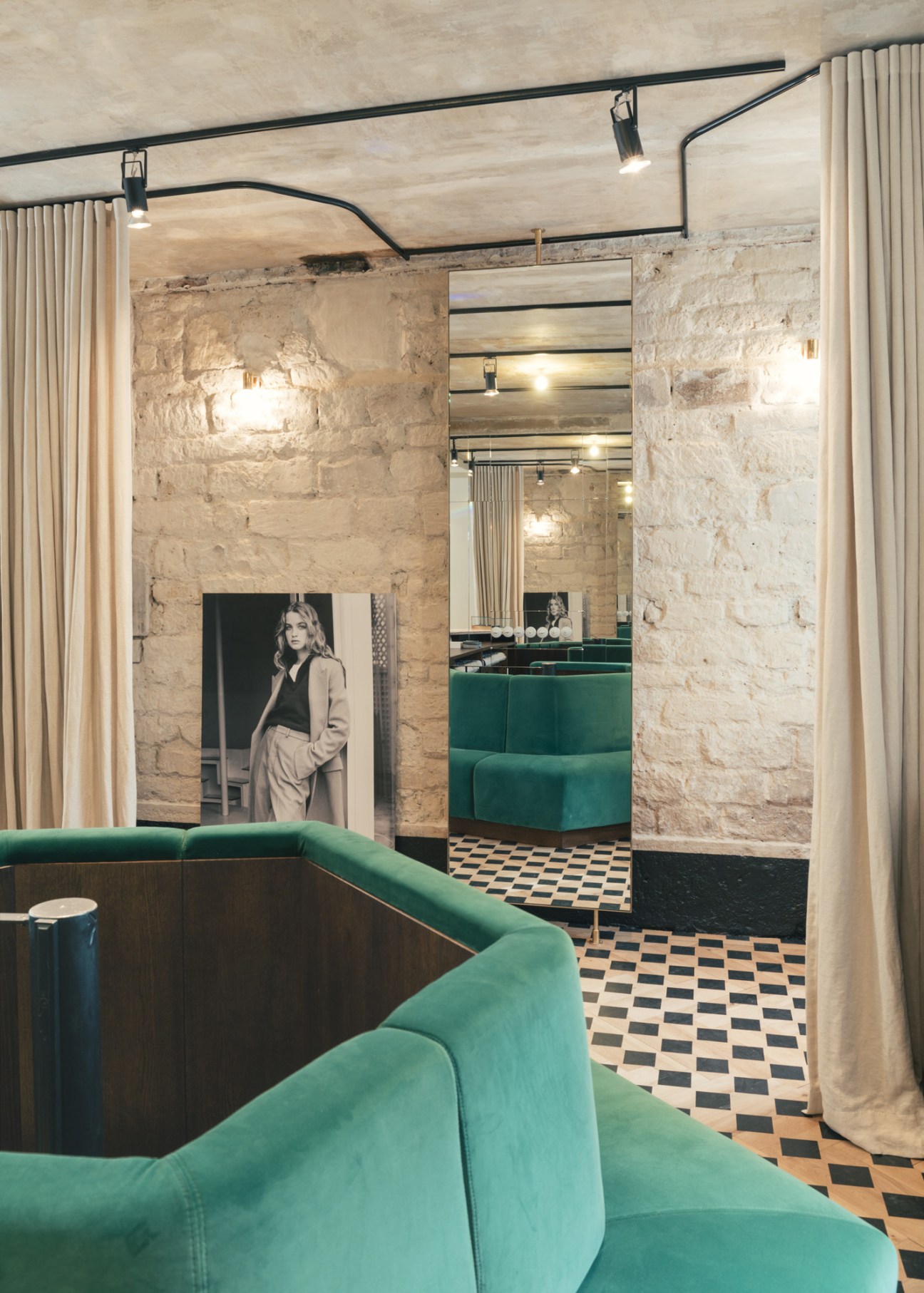 Interior of Ami's women's shop showing green velvet seating, exposed stone walls, and checkerboard flooring.