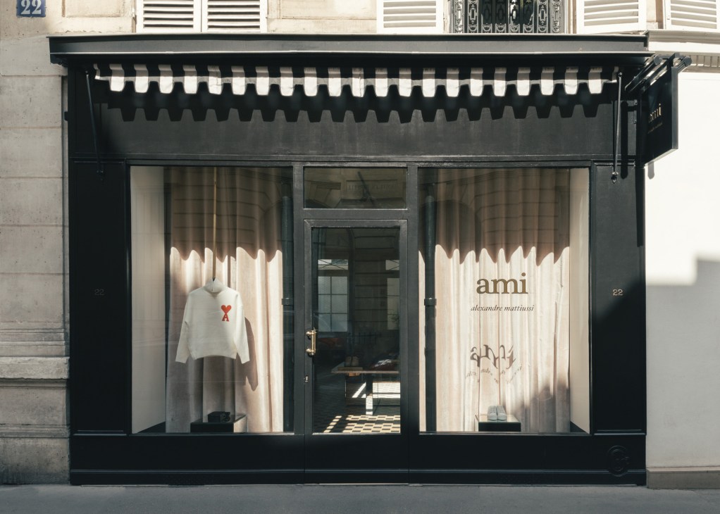Ami women's shop storefront with black facade and striped awning in Saint-Germain-des-Prés, Paris.