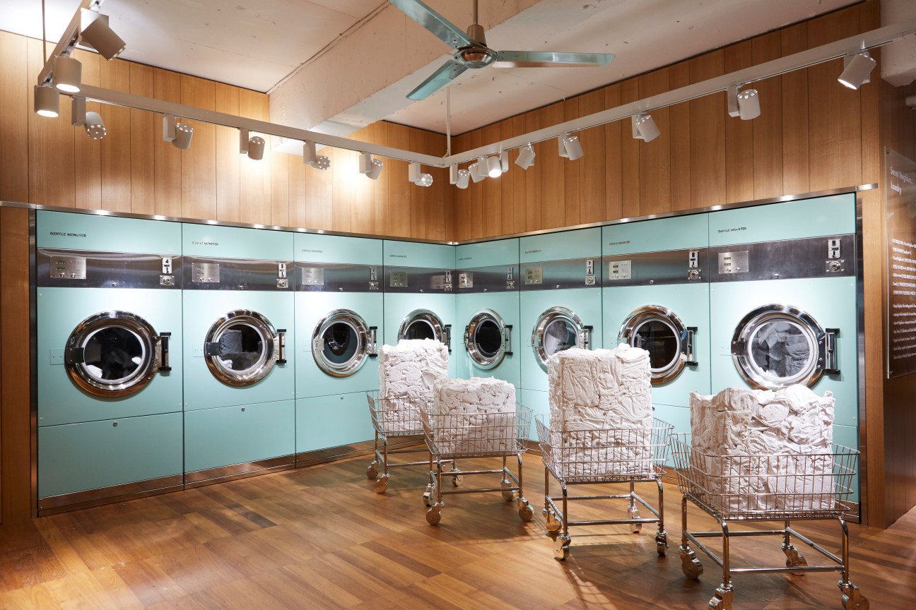 Gentle Monster's Daegu shop with turquoise washing machines and laundry baskets filled with white fabrics.