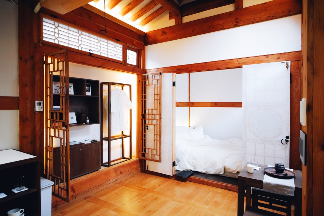 Interior of a newly renovated traditional Korean hanok with wooden beams, white walls, and modern furnishings.
