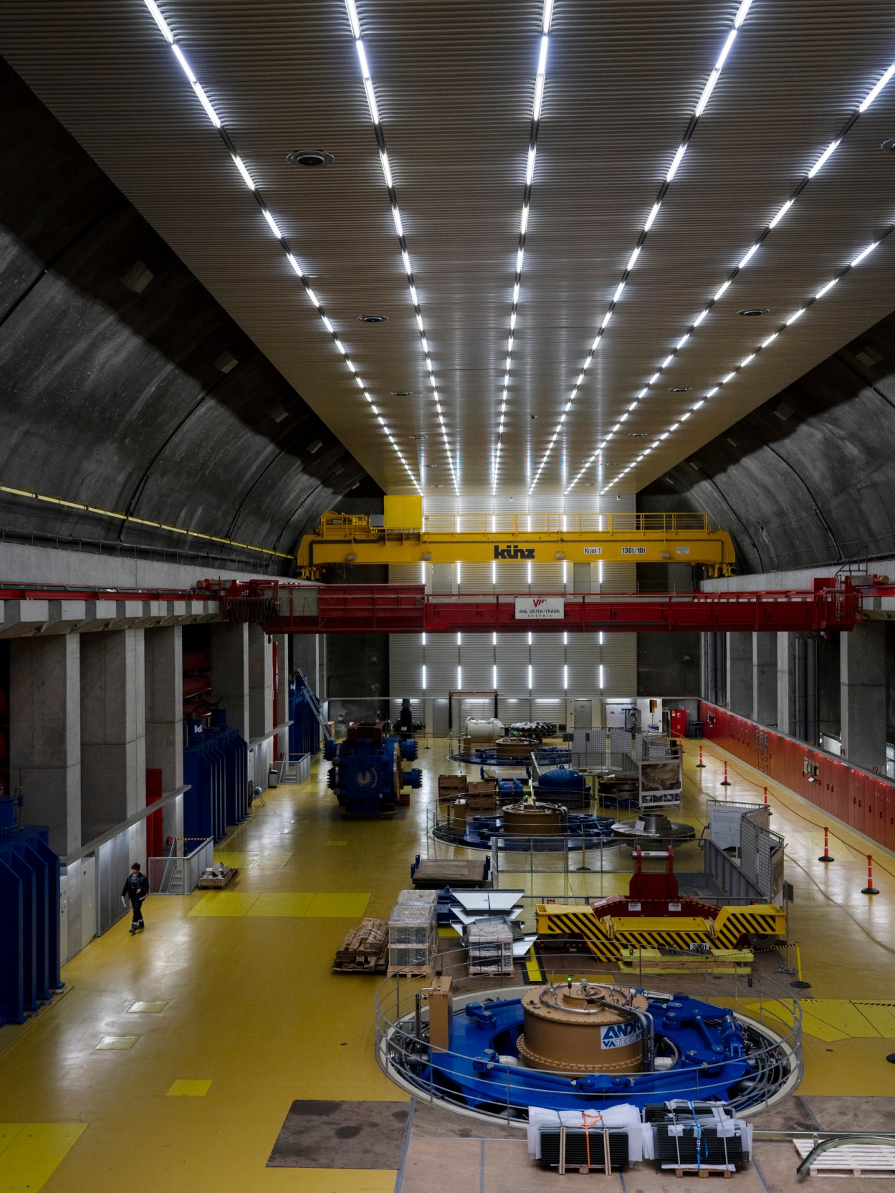 Interior of Kopswerk II hydropower station showing industrial turbine equipment and bright overhead lighting.