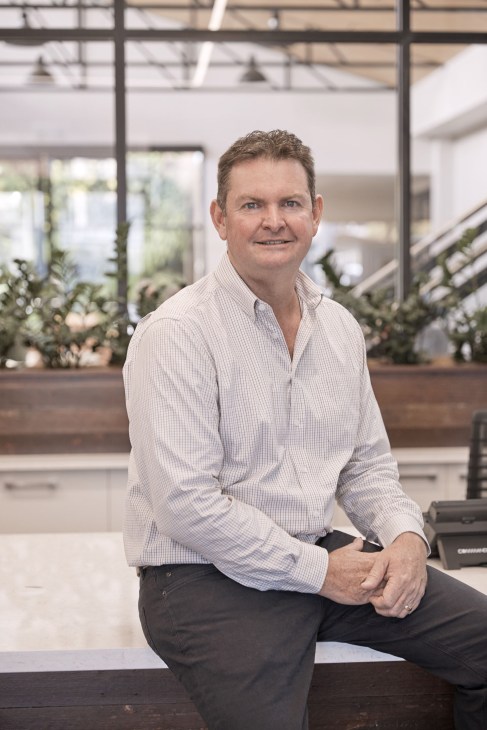 Shane Charles, chairman of Toowoomba and Surat Basin Enterprise, sits in a modern office with plants behind him.