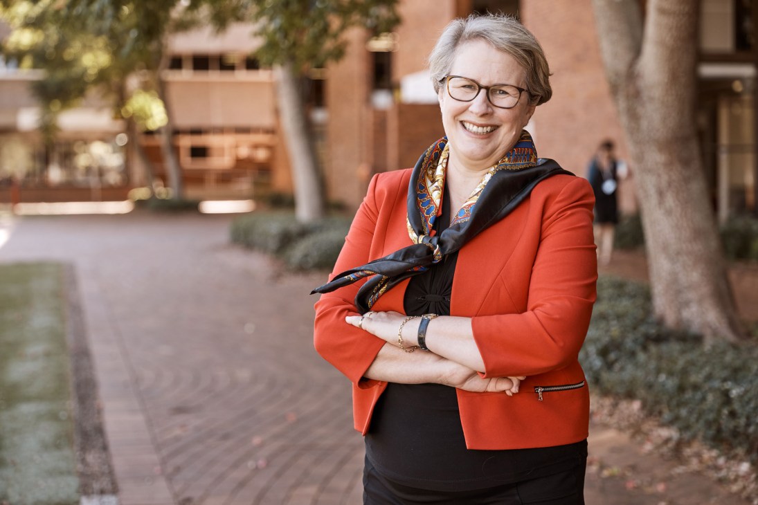 Geraldine Mackenzie, vice-chancellor of the University of Southern Queensland, smiling in an orange blazer on campus.