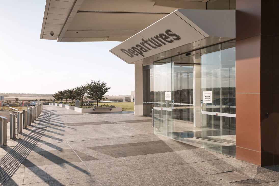 Departures entrance at Brisbane West Wellcamp Airport with signage and glass doors overlooking rural landscape.