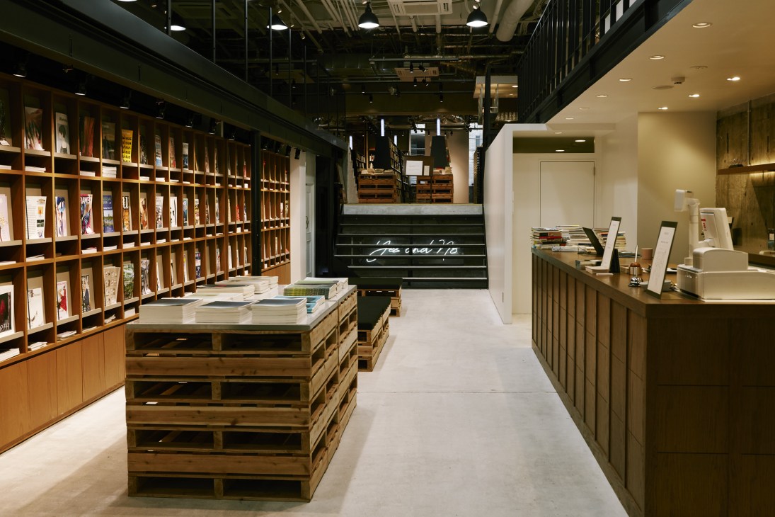 Interior of Bunkitsu bookshop in Tokyo showing wooden shelving with books and a central display table.
