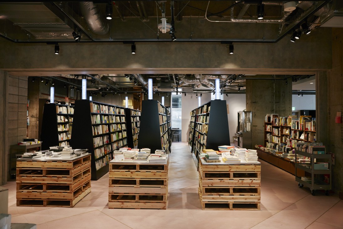 Interior of Bunkitsu bookshop showing wooden crate displays with books, black shelving units, and industrial ceiling.