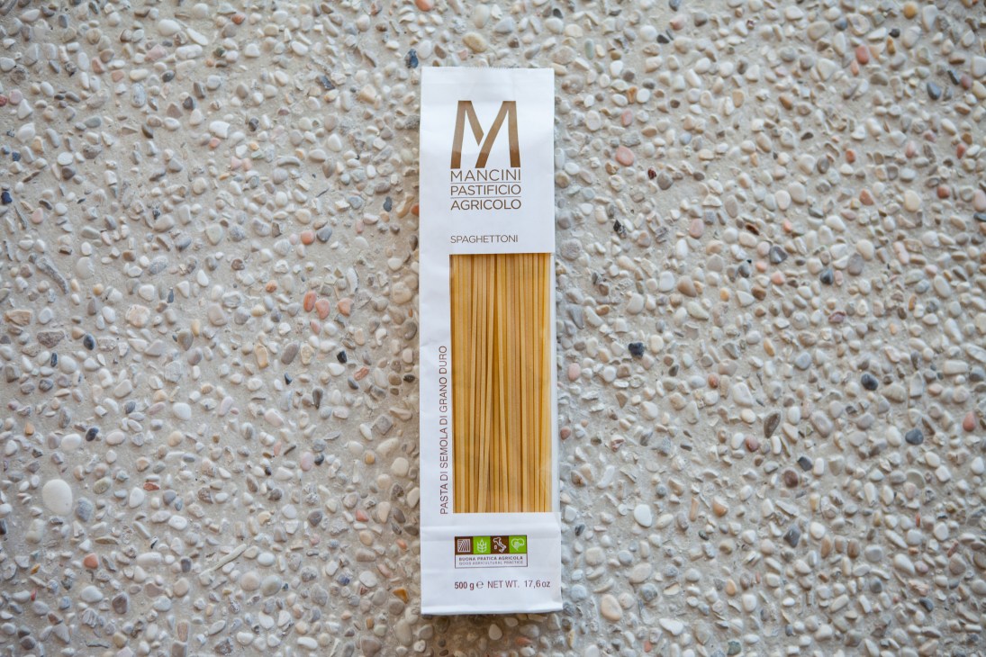 Mancini Pastificio Agricolo spaghettoni pasta package on a textured stone surface.