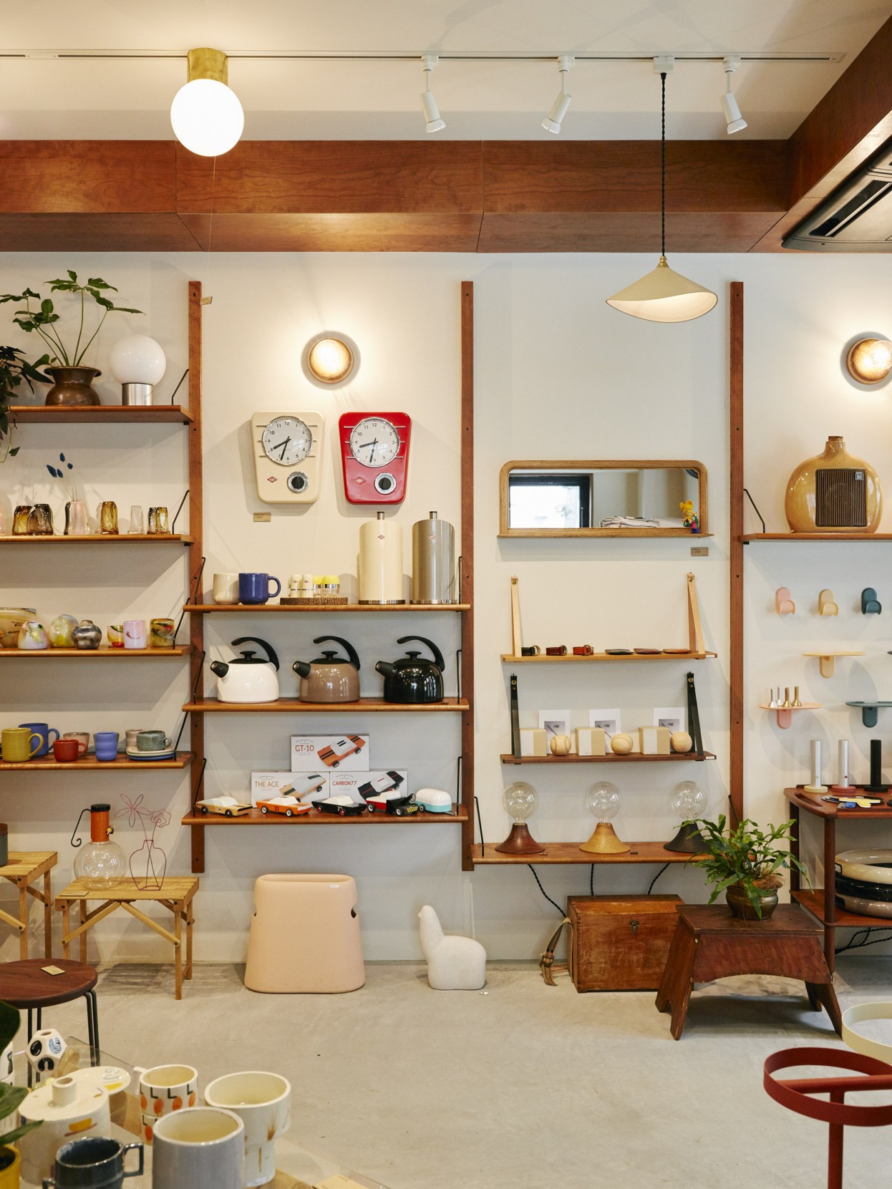 Bullpen furniture shop interior with wooden shelving displaying handmade ceramics, lamps, clocks, and tableware.