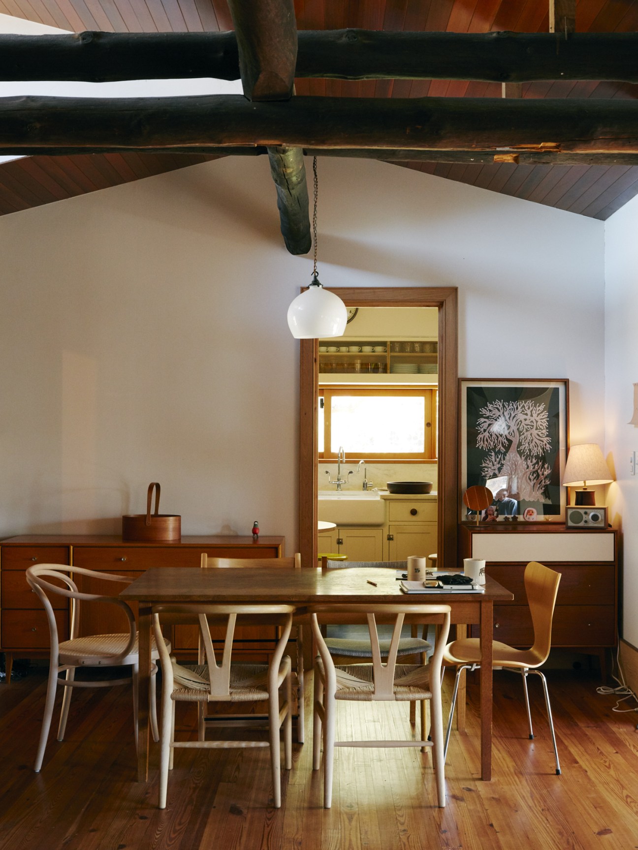 Dining room with wooden table, mixed chairs, and exposed timber beams in a Japanese house.