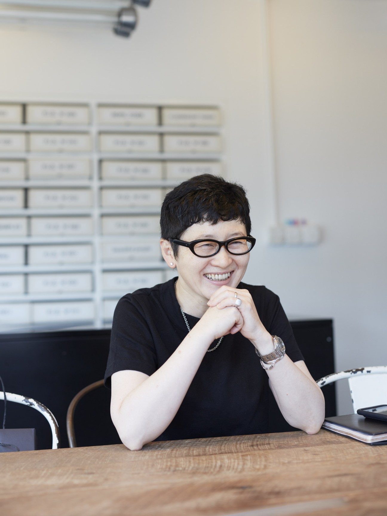 Naomi Hirabayashi, founder of Plug-in Graphic, smiles at her desk in Tokyo.