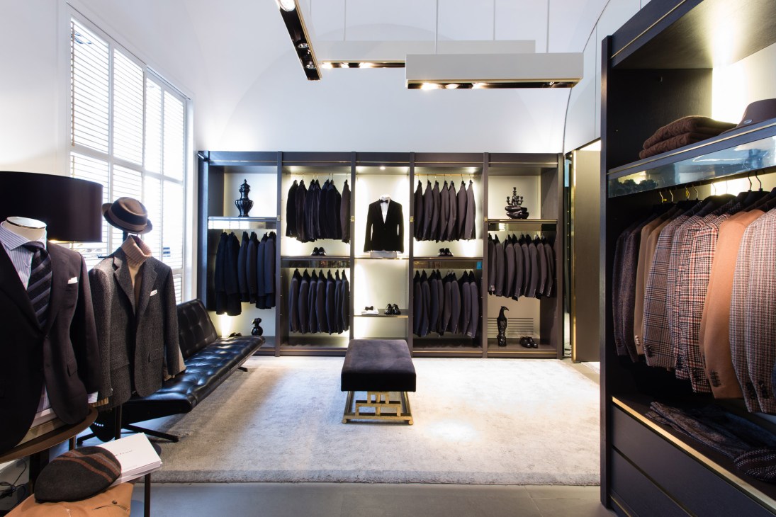 Interior of Nugnes 1920 boutique showing classic menswear display with suits, coats, and accessories on mannequins and rails