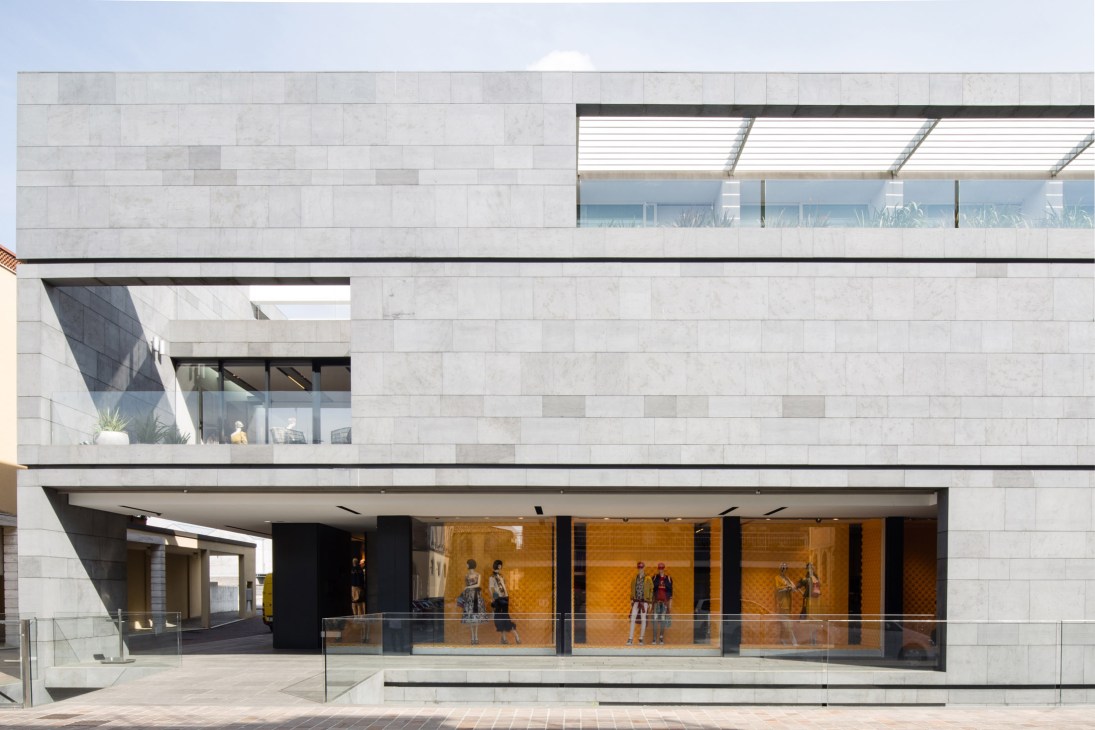 Modern white stone facade of Eraldo boutique with geometric design and large glazed storefront.