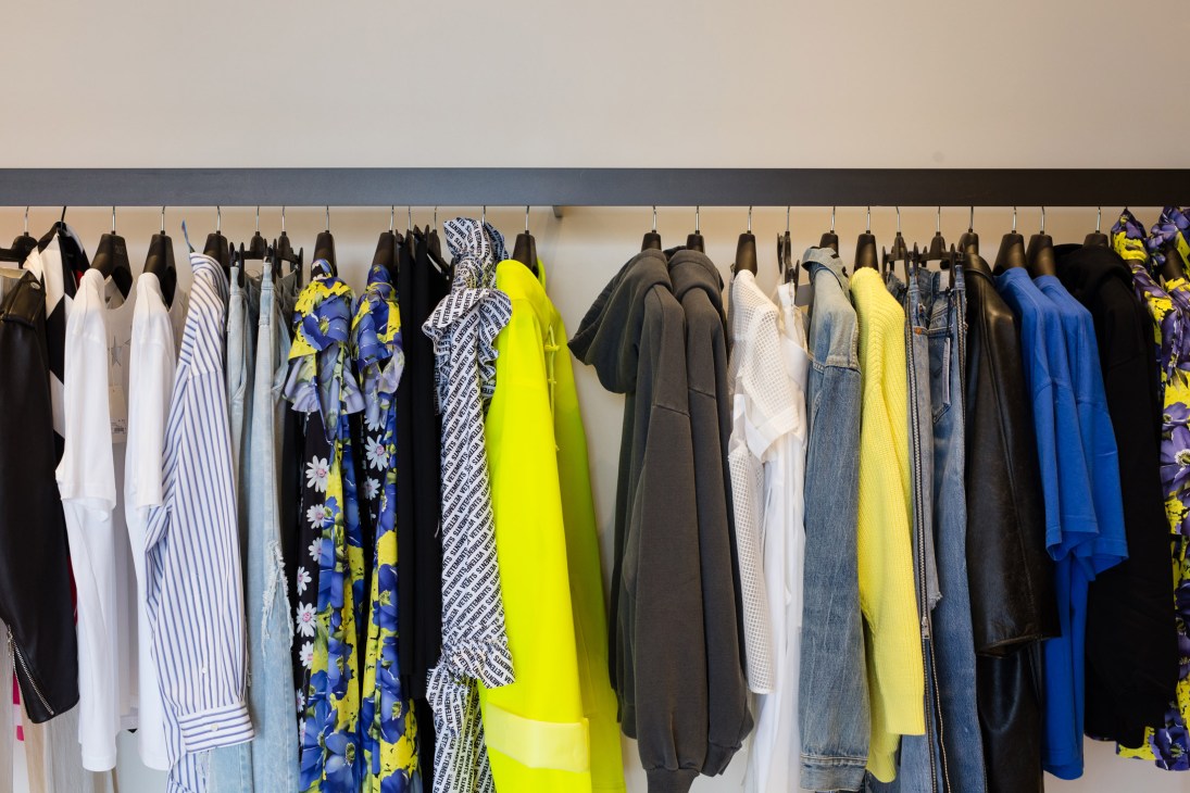 Colorful designer clothing on rails at Eraldo boutique including neon yellow and blue garments