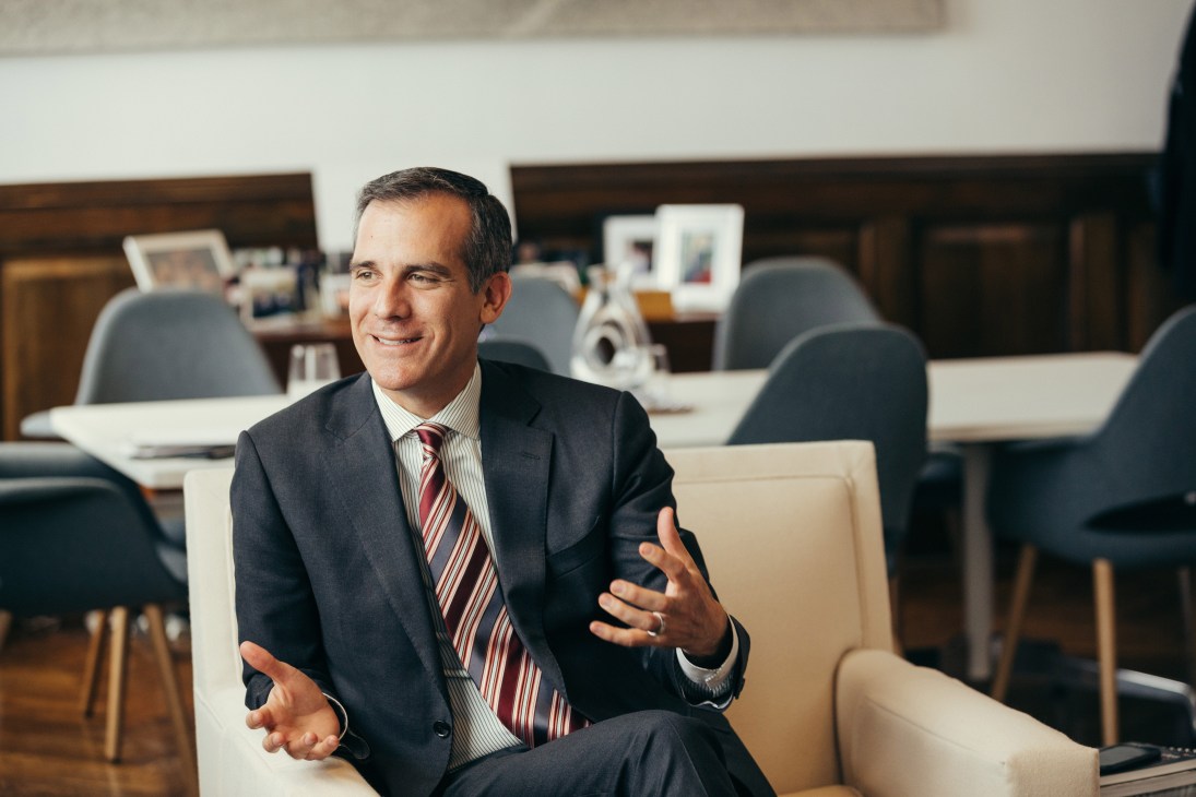 Los Angeles Mayor Eric Garcetti sits in his city hall office discussing his record, wearing a dark suit and striped tie.