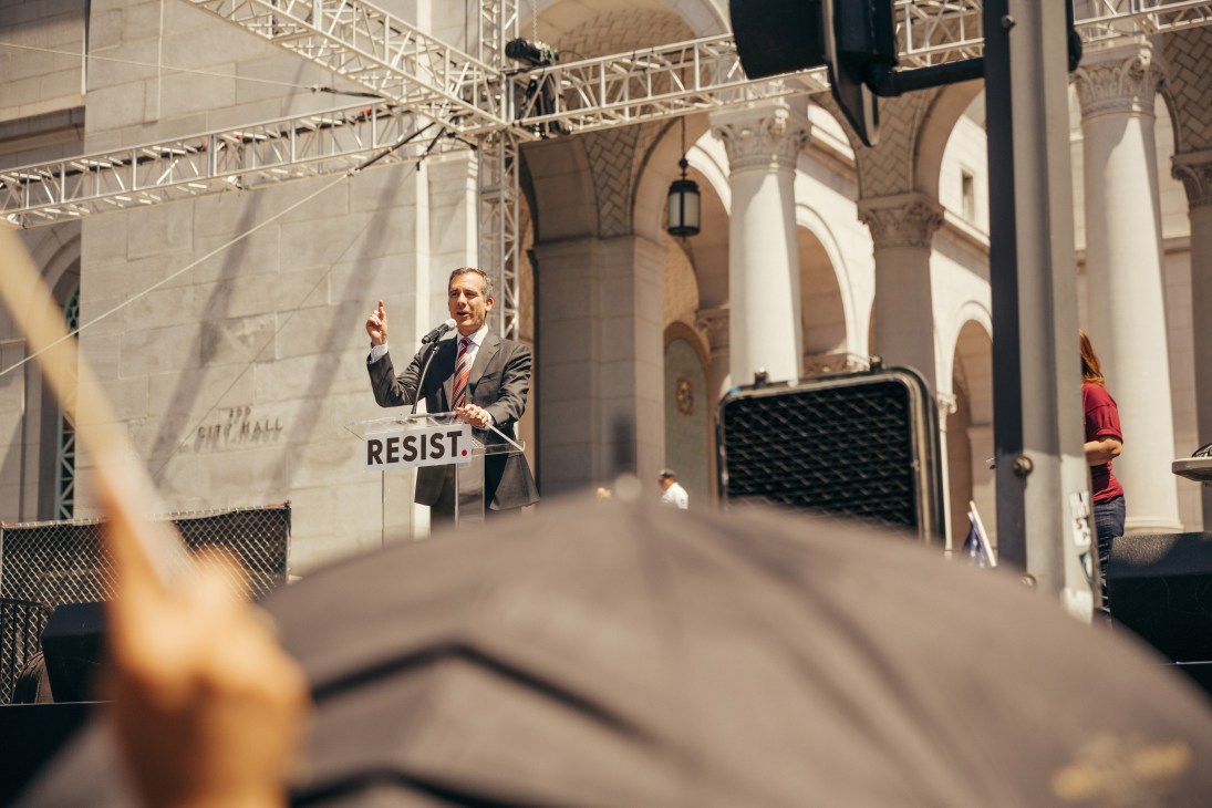 Mayor Eric Garcetti speaking at a podium with a 'Resist' banner at Los Angeles City Hall.