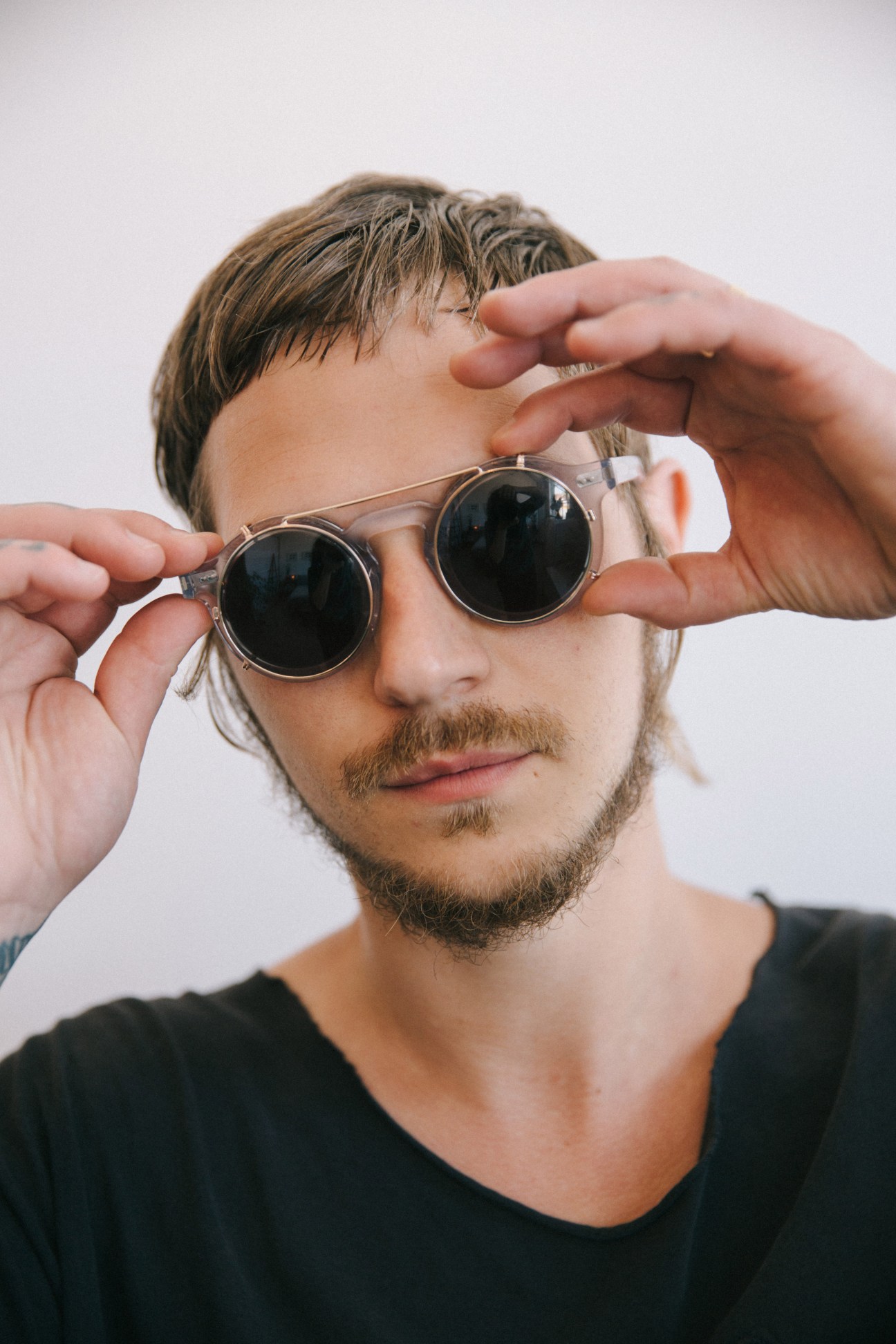 Man wearing round metal-framed sunglasses with dark lenses and black shirt