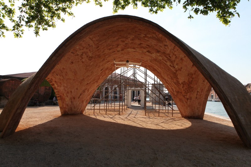 Curved brick archway structure with scaffolding visible through opening at Venice Biennale