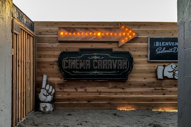 Wooden entrance to Cinema Caravan with illuminated arrow sign and vintage-style signage