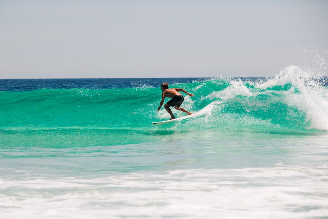 Surfer riding a turquoise wave with white foam spray