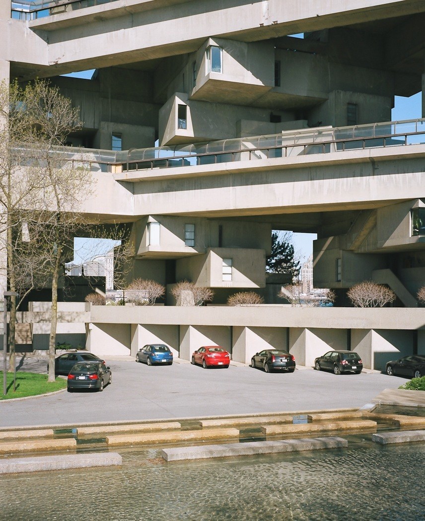 Habitat 67's stacked concrete cube units with car park and St Lawrence River waterfront below.