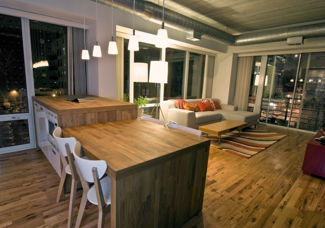 Modern loft apartment with wooden dining table, pendant lighting, and living area with lake views.