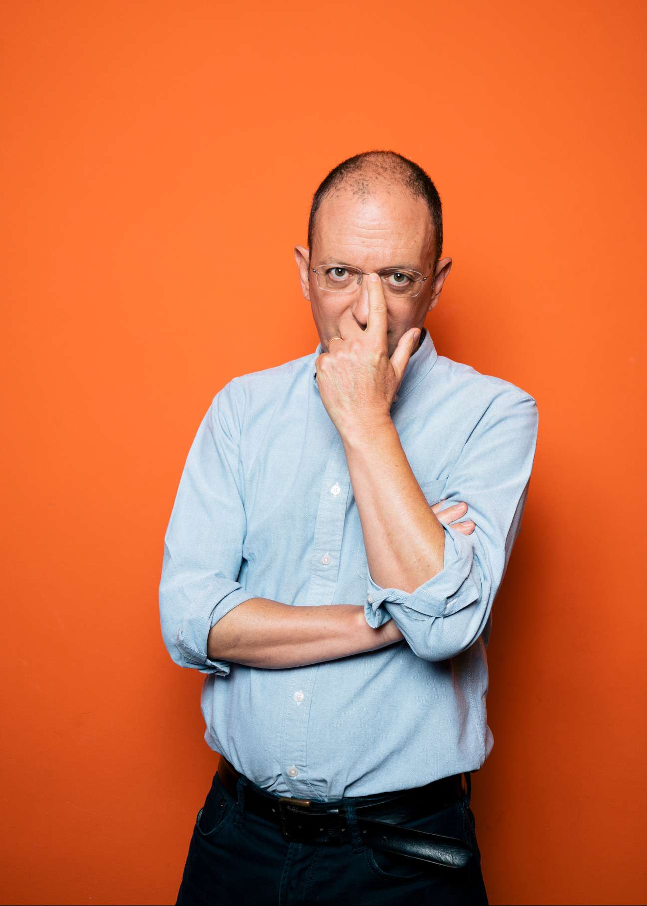 Giovanni De Mauro, editor in chief of Internazionale magazine, poses thoughtfully against an orange background.