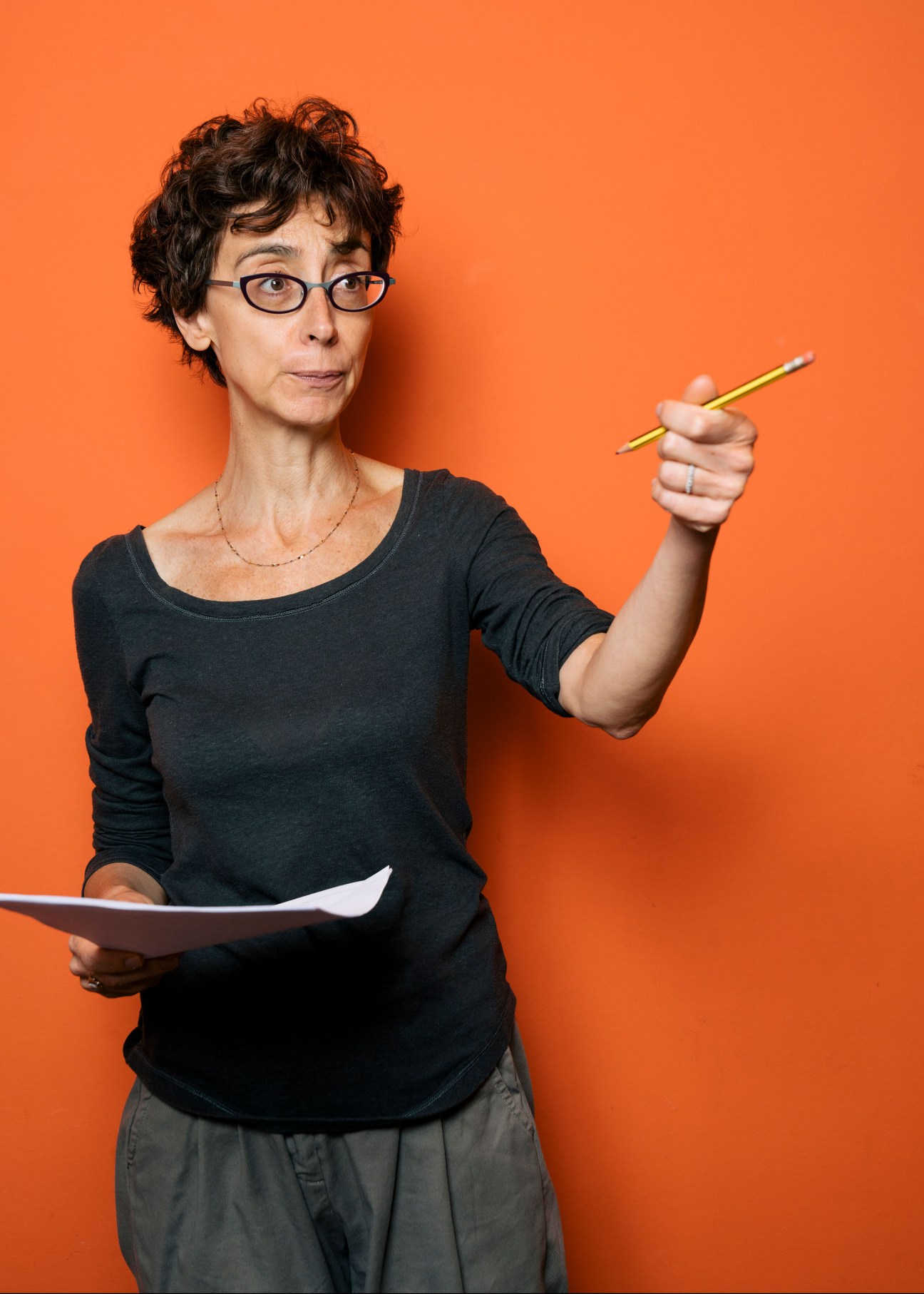 Portrait of Giulia Zoli, copy editor at Internazionale magazine, holding a pencil against an orange background.