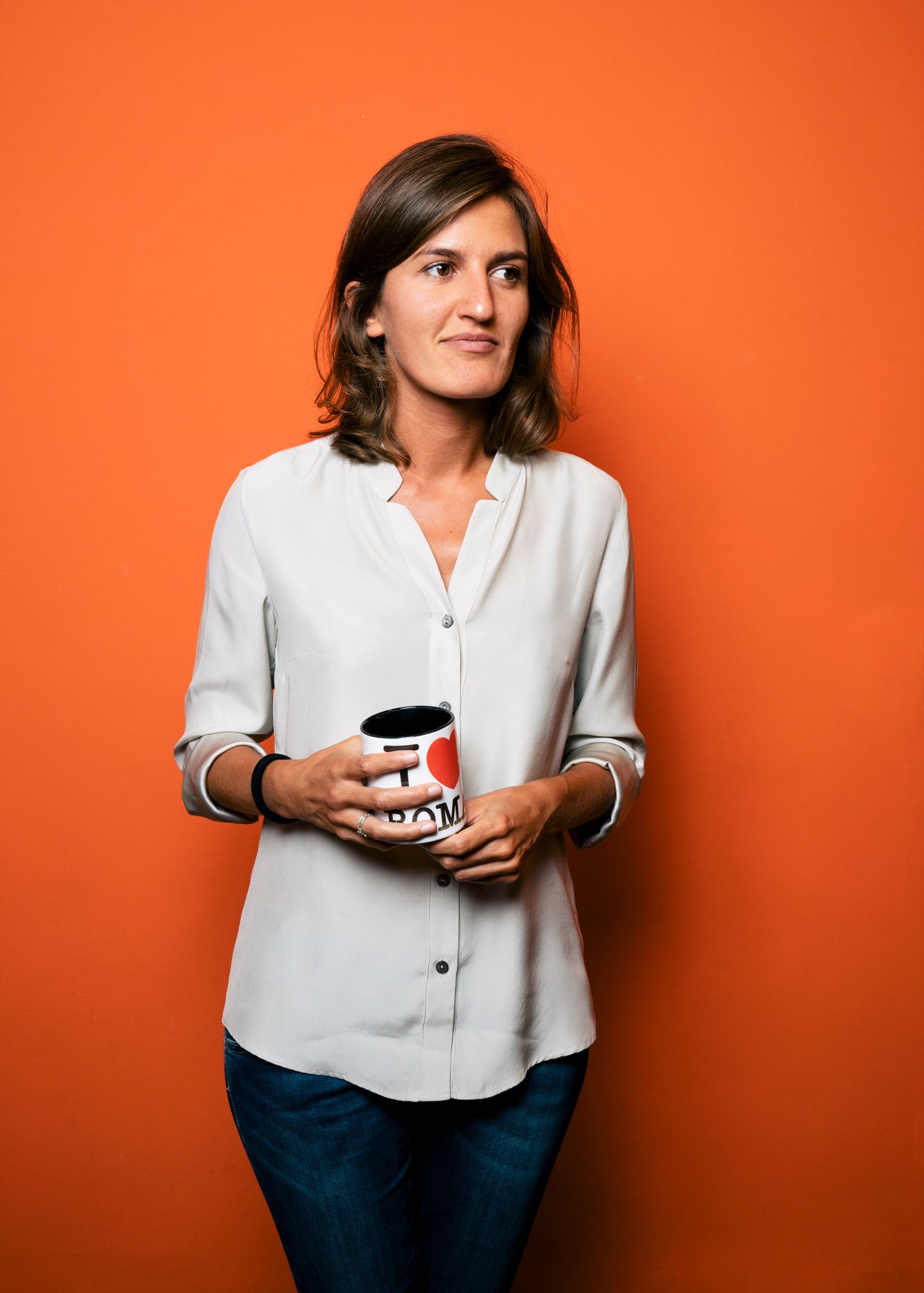 Anna Franchin, copy editor at Internazionale magazine, holding a mug against an orange background.