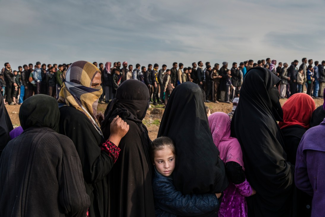 Civilians queuing for aid in West Mosul, including women and children in traditional dress.