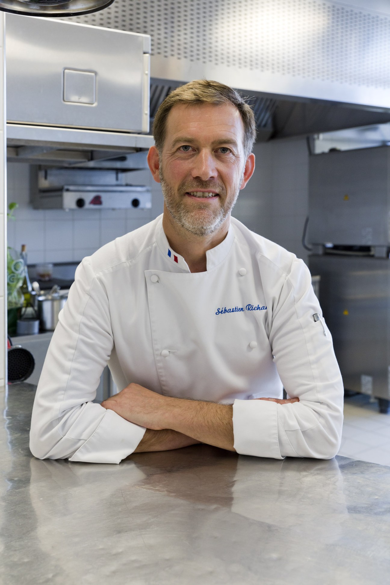Chef Sébastien Richard in white chef's jacket with embroidered name in professional kitchen