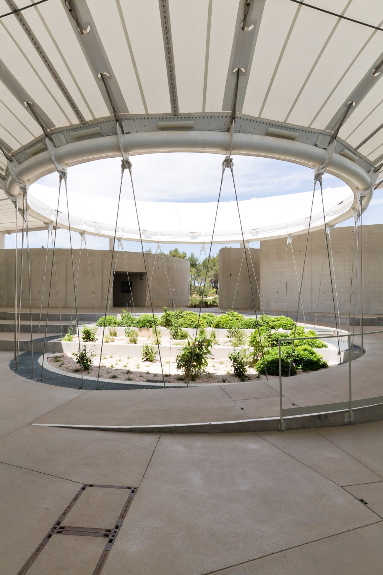 Interior view of a circular architectural space with metallic canopy and central garden area at The Camp.