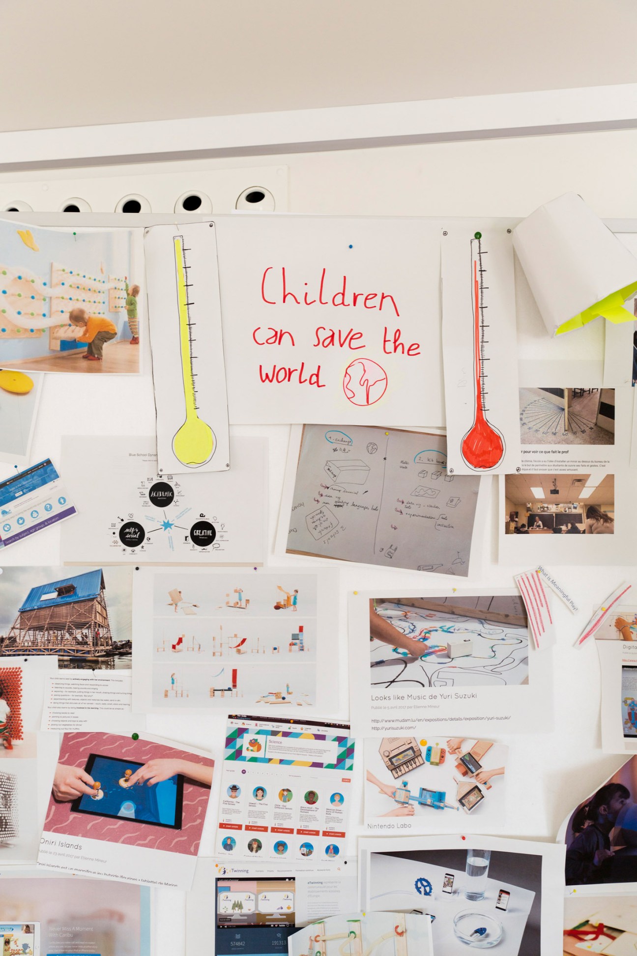 Wall display of creative project sketches and prototypes with a central sign reading 'Children can save the world'