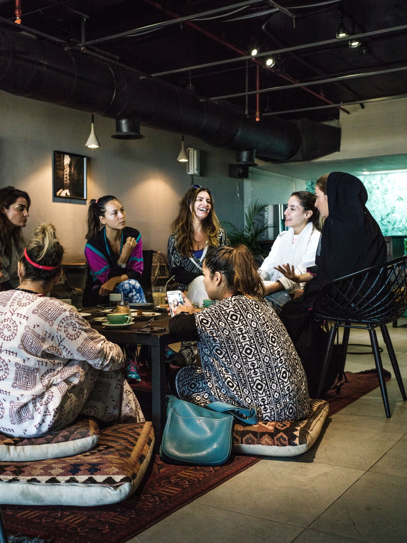 Women gathered around a table at Medd Café in Jeddah, conversing over refreshments.