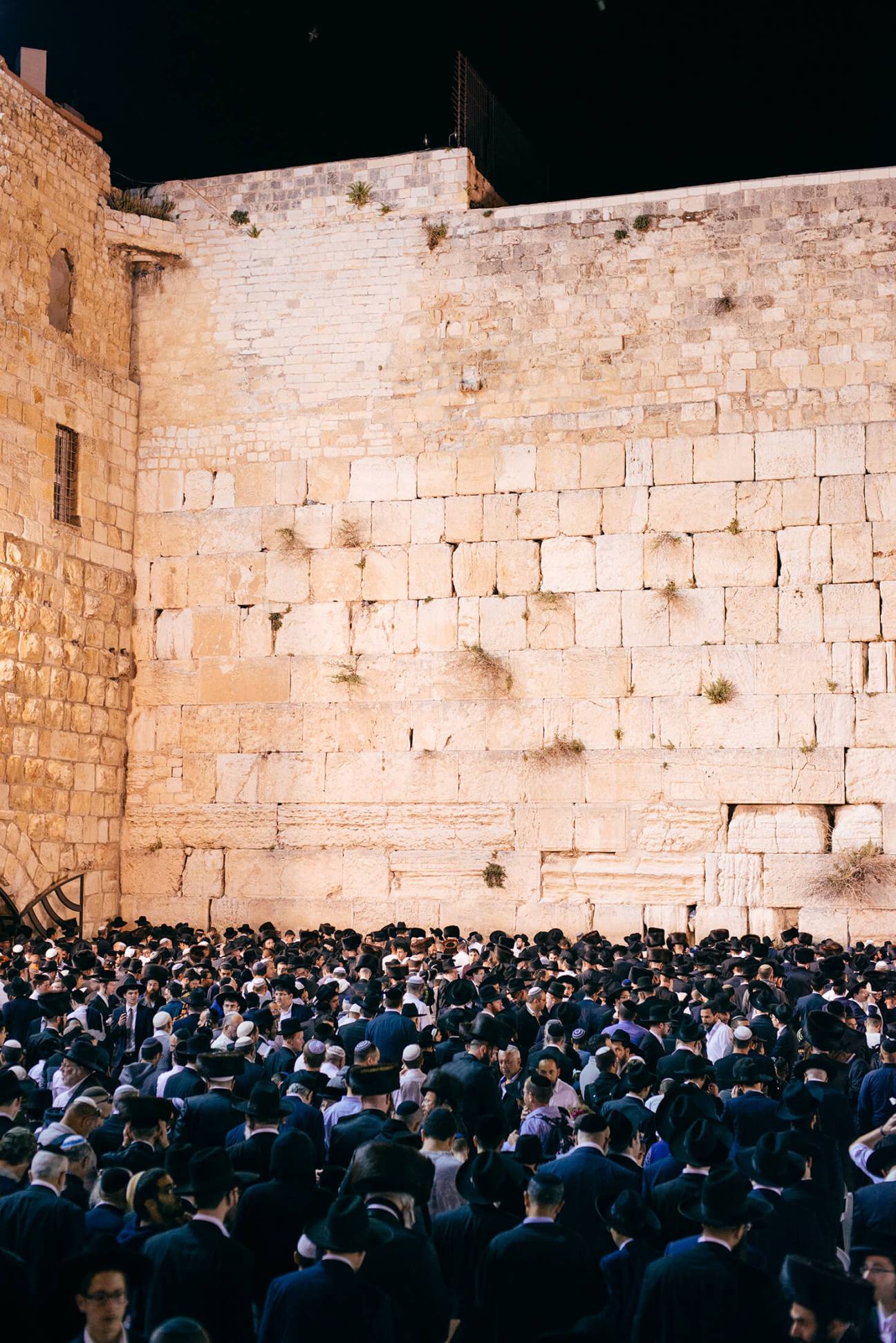 Large crowds of people gathered at night at the Western Wall in Jerusalem.