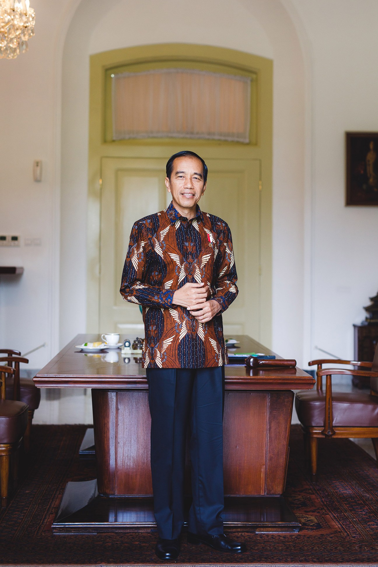 Indonesian President Joko Widodo stands at his presidential desk wearing a traditional batik shirt.