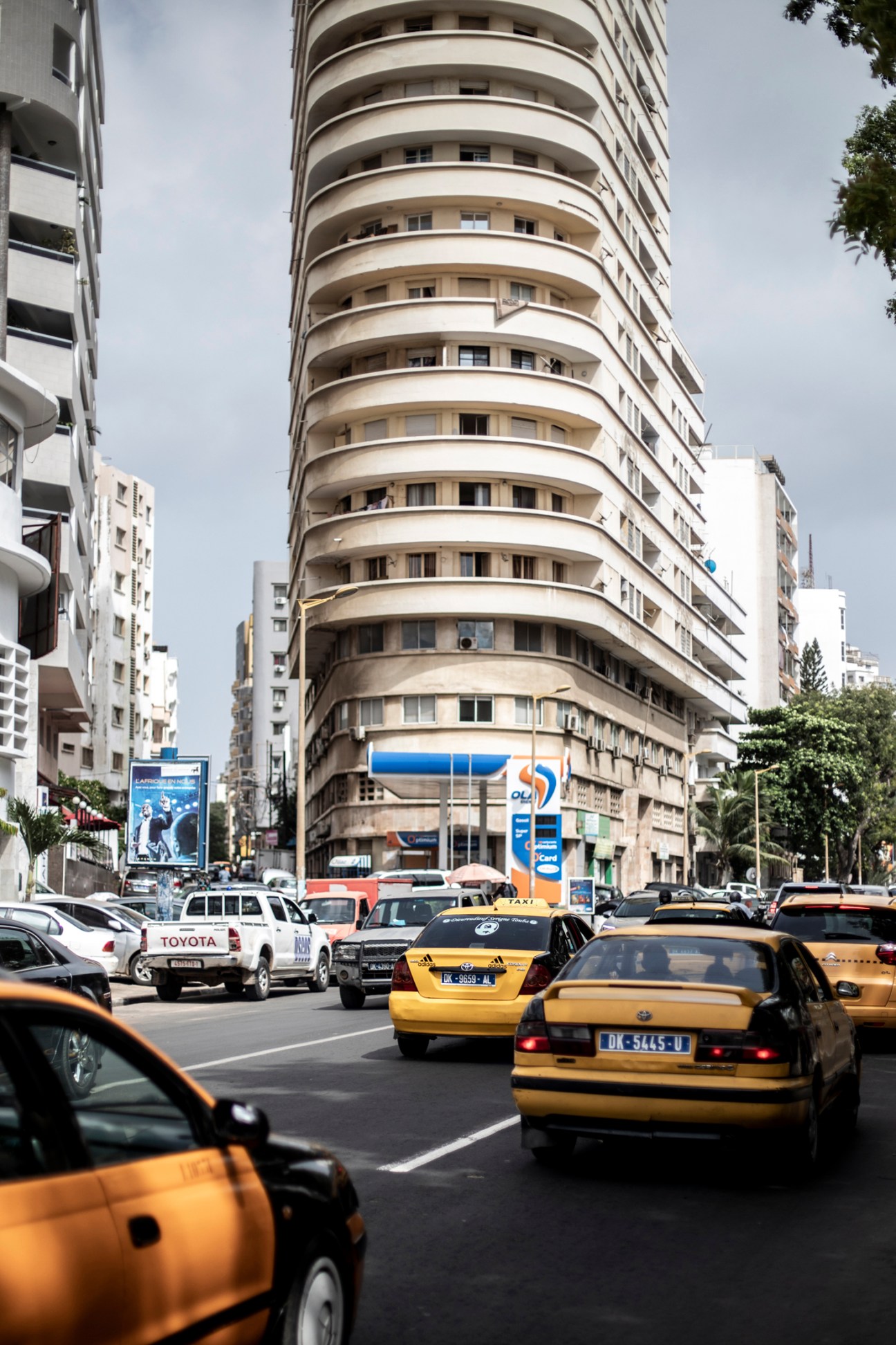 Busy street scene with yellow taxis and cars in traffic surrounded by multi-story buildings in Dakar