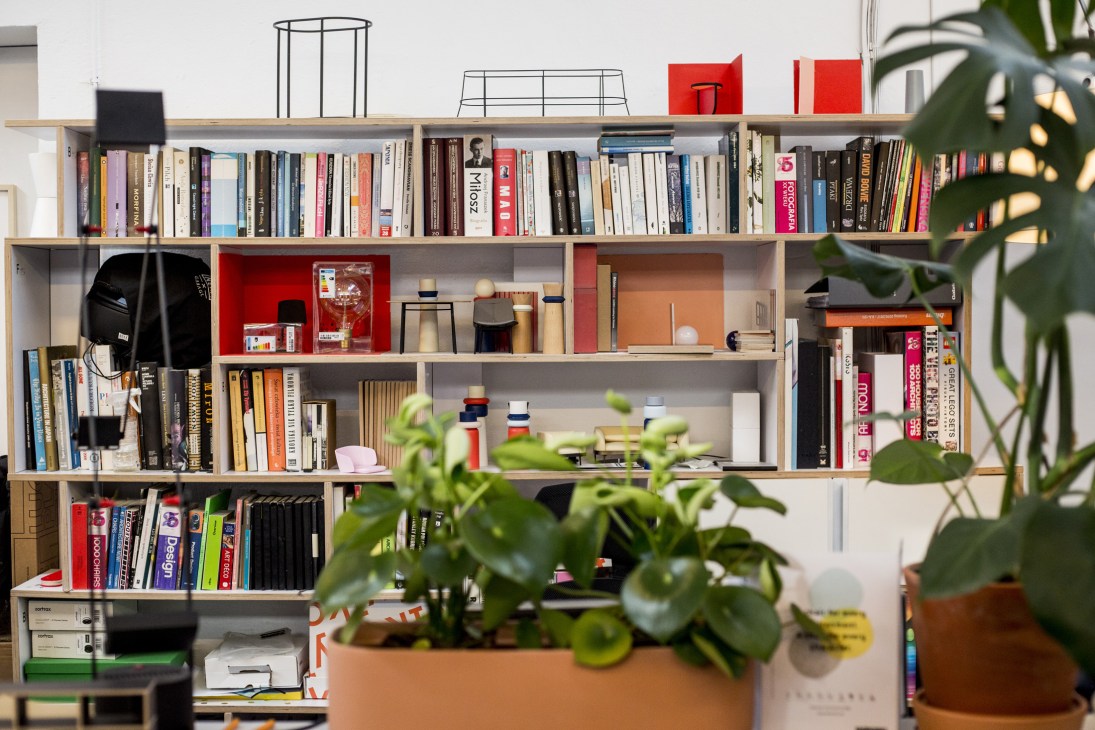 Bookcase shelving unit by Tylko filled with books, plants, and decorative objects.
