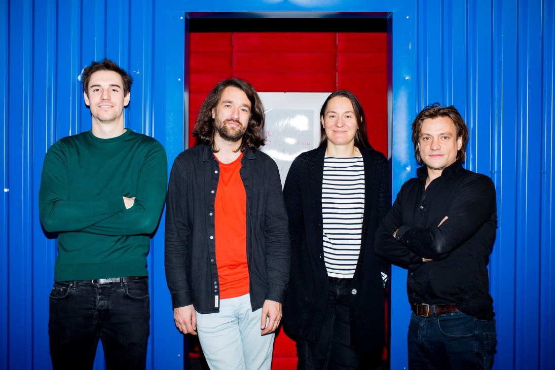 Four members of Tylko furniture company posing against a blue and red wall backdrop.