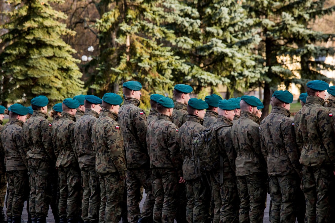 Polish military cadets in camouflage uniforms and blue berets stand in formation during a briefing at the Military University of Land Forces in Wroclaw.